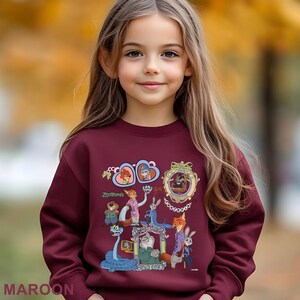 May include: A maroon sweatshirt with a colourful Zootopia character design. The design includes various characters in ornate frames and the word "Zootopia". The word "MAROON" is printed at the bottom of the sweatshirt.