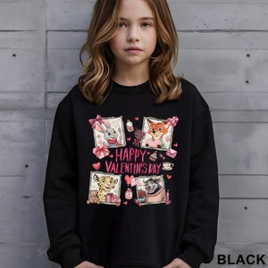May include: Black sweatshirt featuring four cartoon character portraits with Valentine's Day themes. The words "Happy Valentine's Day" are in pink. The word "BLACK" is at the bottom right.