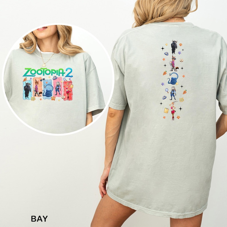 May include: Light gray t-shirt featuring the text "ZOOTOPIA 2" with colorful character illustrations on the front. The back of the shirt has vertical illustrations of characters and objects from the movie.