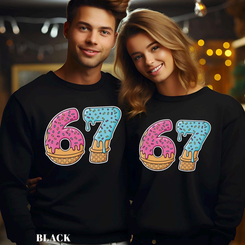 May include: Black sweatshirts featuring a colorful '67' design. The '6' is a pink donut with sprinkles, and the '7' is blue with sprinkles, both on a waffle cone base. The word 'BLACK' is at the bottom.