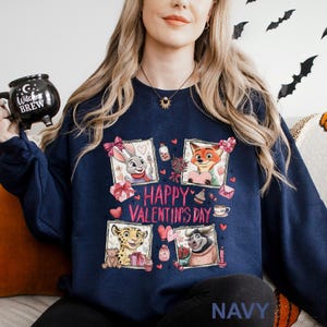 May include: Navy blue sweatshirt with a Valentine's Day graphic. The design features cartoon characters in framed images, with the text "Happy Valentine's Day" in pink. The word "NAVY" is printed at the bottom.