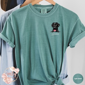 May include: Light green t-shirt with a black Labrador Retriever peeking over the top of a pocket. The dog's name, "Bear", is written in cursive below the dog.