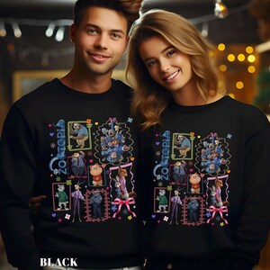 Puede incluir: Sudaderas negras con un dise&ntilde;o gr&aacute;fico colorido de personajes de la pel&iacute;cula Zootopia, incluyendo un perezoso y otros animales, con la palabra "Zootopia". El dise&ntilde;o est&aacute; enmarcado con detalles rosas y azules. Llevadas por dos personas.