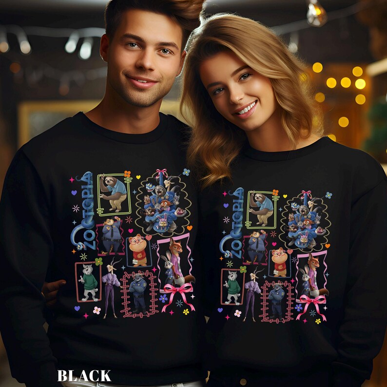 Puede incluir: Sudaderas negras con un dise&ntilde;o gr&aacute;fico colorido de personajes de la pel&iacute;cula Zootopia, incluyendo un perezoso y otros animales, con la palabra "Zootopia". El dise&ntilde;o est&aacute; enmarcado con detalles rosas y azules. Llevadas por dos personas.