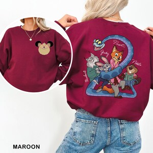 Op de afbeelding: Bordeaux sweatshirt met cartoon illustraties op de voor- en achterkant. De voorkant heeft een muisontwerp en de achterkant heeft een cartoon slang en karakter illustraties. De namen "Judy", "Nick" en "Nibbles" staan op de achterkant.