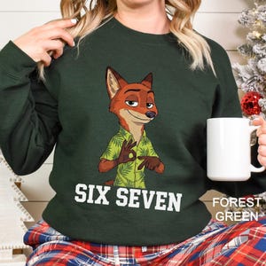May include: Forest green sweatshirt featuring a cartoon fox character in a Hawaiian shirt. The text "SIX SEVEN" is printed in white. The sweatshirt is a solid color with the words "FOREST GREEN" printed on the bottom right.