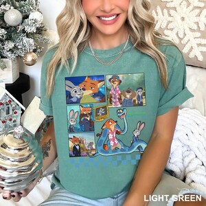 以下が含まれることがあります： アニメ映画「ズートピア」のキャラクターが登場するコミックストリップデザインのライトグリーンのTシャツ。デザインには、ニック・ワイルド、ジュディ・ホップス、その他のキャラクターの画像が含まれています。シャツは袖をまくり上げており、下部に「LIGHT GREEN」の文字があります。