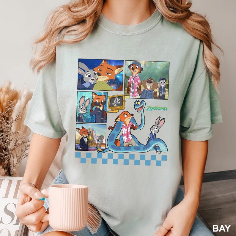 以下が含まれることがあります： 映画「ズートピア」のキャラクターが登場するコミックストリップデザインのライトグリーンのTシャツ。デザインには、キツネ、ウサギ、その他のキャラクターがさまざまなシーンで登場します。「ズートピア」の文字は緑色で印刷されています。