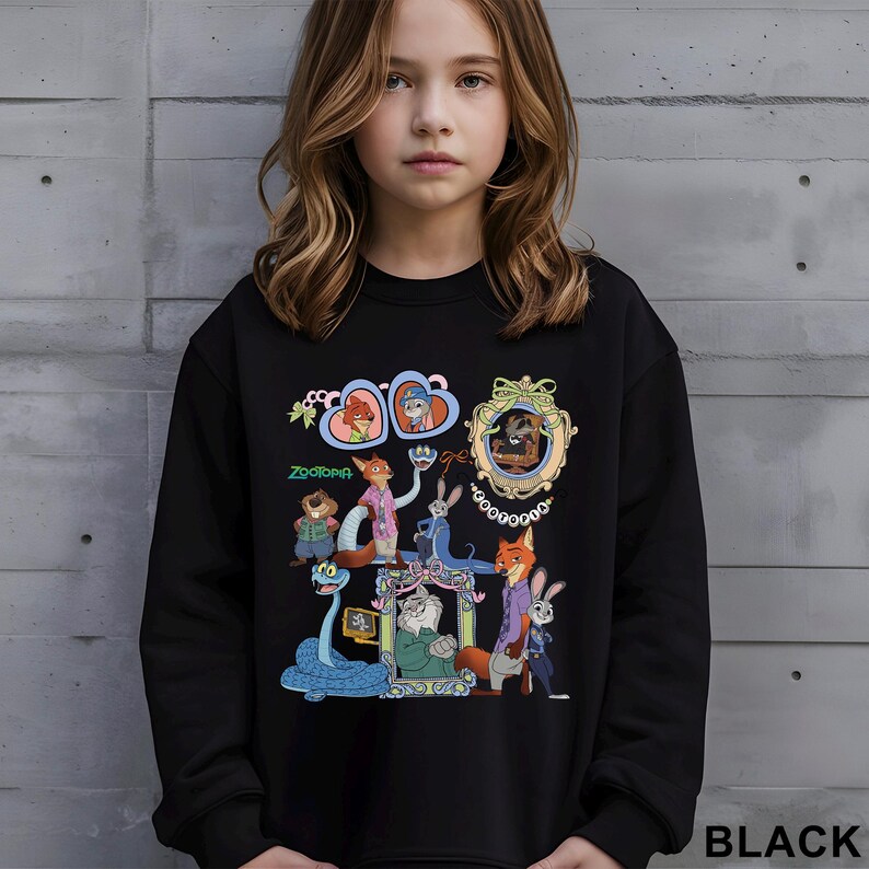 May include: Black sweatshirt with a colourful graphic of characters from the animated film "Zootopia." The design includes various animal characters in ornate frames and the movie title. The word "BLACK" is printed at the bottom right.