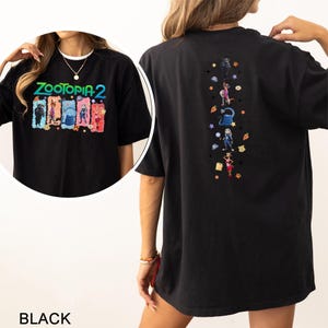 May include: Black Zootopia 2 graphic t-shirt. The front features the text "Zootopia 2" above cartoon characters. The back has a vertical design of Zootopia characters and icons. The shirt is a casual, oversized fit.