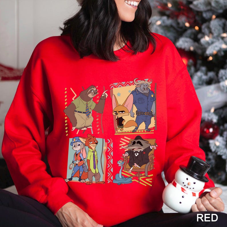 May include: A red sweatshirt featuring a colorful graphic of characters from the animated movie Zootopia. The design includes images of a sloth, fox, bunny, and other characters. The word "RED" is printed in white at the bottom right.