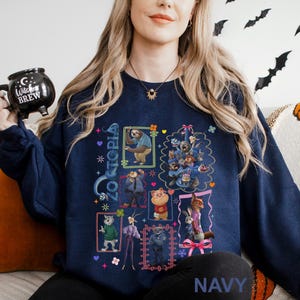 Puede incluir: Sudadera azul marino con un gr&aacute;fico colorido de personajes de la pel&iacute;cula Zootopia. El dise&ntilde;o incluye ilustraciones enmarcadas de personajes de animales, con la palabra "Zootopia" en una fuente estilizada. La palabra "NAVY" est&aacute; impresa en la parte inferior.