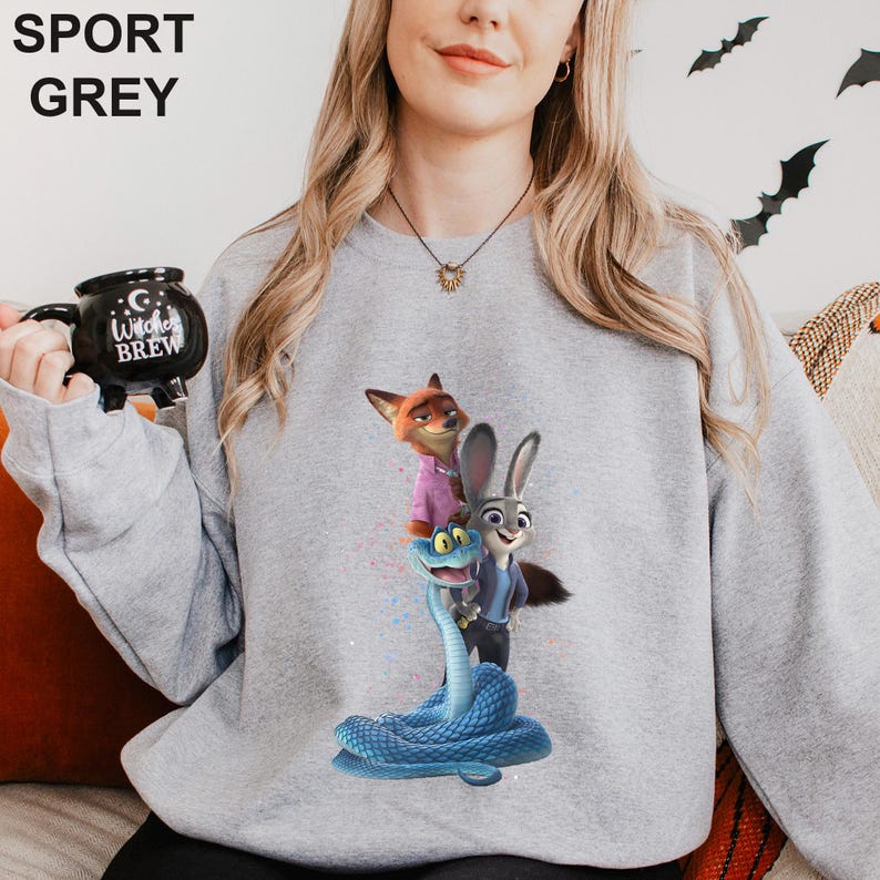 K&ouml;nnte beinhalten: Sportgraues Sweatshirt mit einem farbenfrohen Aufdruck von Charakteren aus dem Animationsfilm Zootopia. Das Design zeigt einen Fuchs, ein Kaninchen und eine Schlange. Das Sweatshirt hat lange &Auml;rmel und einen Rundhalsausschnitt.