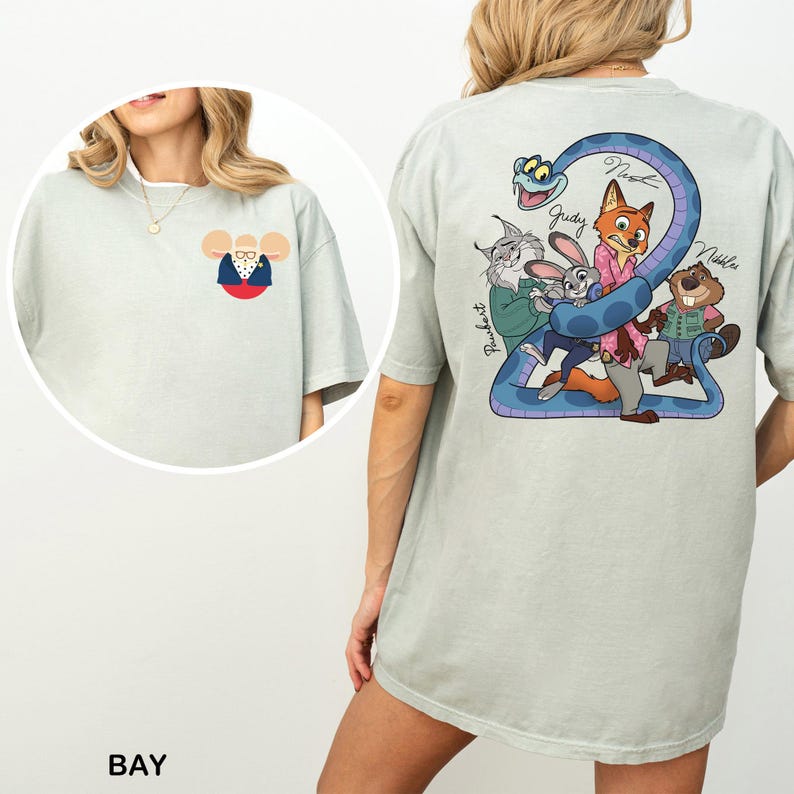 May include: Pale green t-shirt with a cartoon illustration on the back, including a blue snake and various animal characters. The front displays a small cartoon mouse in glasses and a suit. The word "BAY" is printed at the bottom of the image.