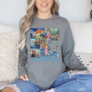 以下が含まれることがあります： アニメ映画「ズートピア」のキャラクターが描かれた、グレーの長袖シャツ。グラフィックには、さまざまなシーンと「ズートピア」の文字が描かれた複数のパネルが含まれています。シャツは柔らかい素材で作られています。