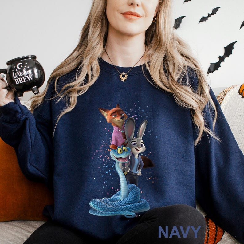 K&ouml;nnte beinhalten: Marineblaues Sweatshirt mit einer farbenfrohen Grafik von Zeichentrickfiguren. Das Design zeigt einen Fuchs in einem rosa Hemd, ein Kaninchen in einem blauen Anzug und eine blaue Schlange. Das Wort "NAVY" ist unten aufgedruckt.