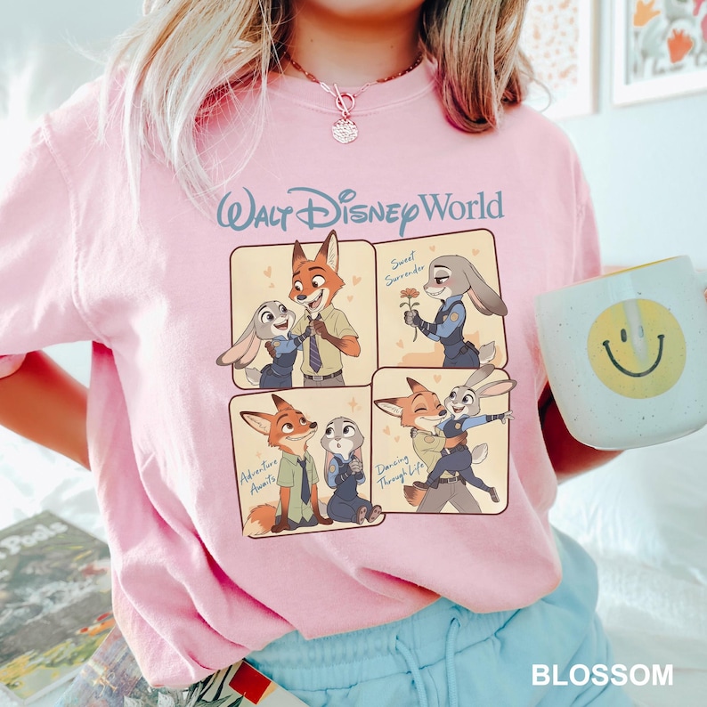 K&ouml;nnte beinhalten: Ein hellrosa T-Shirt mit einem Walt Disney World-Aufdruck, der vier Felder mit Nick Wilde und Judy Hopps aus Zoomania zeigt. Die Felder enthalten die Texte Sweet Surrender, Adventure Awaits und Dancing Through Life im Cartoon-Stil.