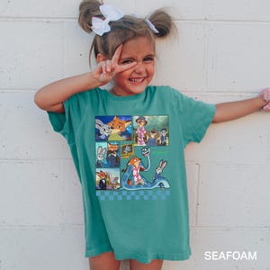 以下が含まれることがあります： 映画のキャラクターの漫画グラフィックが特徴のティールTシャツ。グラフィックは、キツネとウサギの画像コラージュです。シャツの底には「SEAFOAM」という文字がプリントされています。