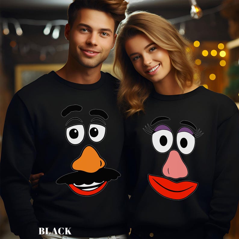 May include: Black sweatshirts featuring Mr. and Mrs. Potato Head faces. The Mr. Potato Head sweatshirt has a black mustache, orange nose, and red mouth. The Mrs. Potato Head sweatshirt has purple eyelashes, a pink nose, and a red mouth.