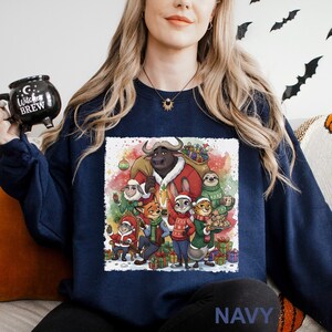 Op de afbeelding: Marineblauwe sweatshirt met een feestelijke afbeelding van cartoon dieren in kerstoutfits. Het ontwerp bevat een stier, een luiaard, een konijn en andere personages, omringd door cadeaus en sneeuw. Het woord "NAVY" staat onderaan gedrukt.