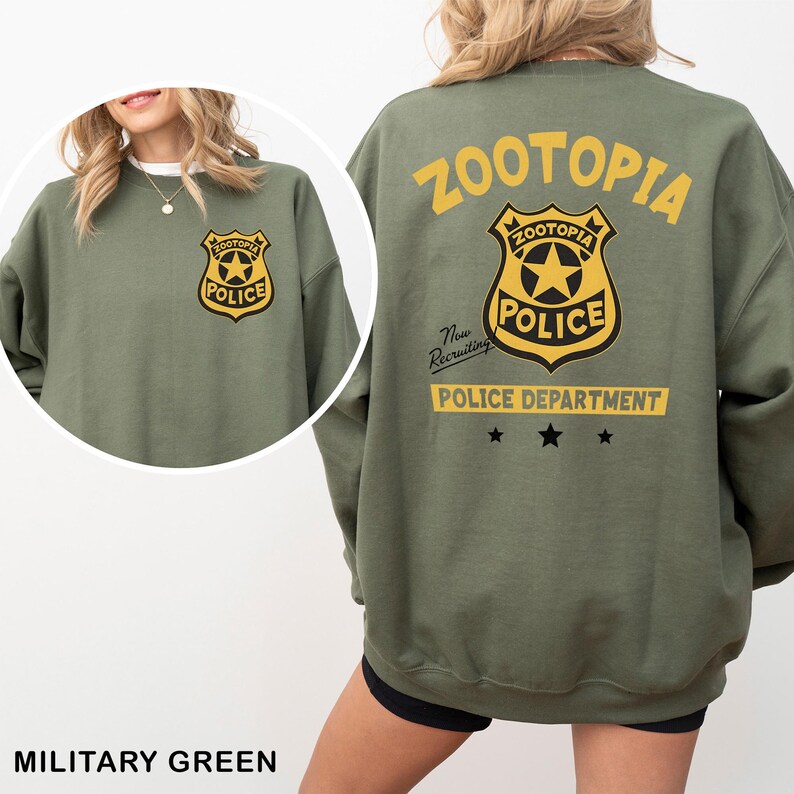 Puede incluir: Sudadera verde militar con una insignia del Departamento de Polic&iacute;a de Zootopia en la parte delantera y trasera. El dise&ntilde;o trasero incluye la palabra "Zootopia" encima de la insignia y "Police Department" debajo. La sudadera tiene mangas largas.