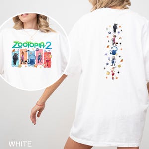 May include: White t-shirt featuring the text "ZOOTOPIA 2" with cartoon characters on the front. The back of the shirt has a vertical design with more cartoon characters and stars. The shirt is a casual, oversized fit.