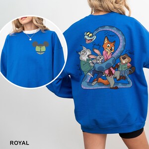 Op de afbeelding: Koningsblauw sweatshirt met een cartoonafbeelding op de rug met personages uit een film. De voorkant heeft een Mickey Mouse-hoofdontwerp. De sweatshirt is effen van kleur en heeft een ronde hals.