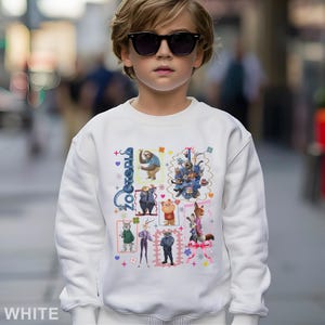 Puede incluir: Sudadera blanca con un gr&aacute;fico colorido de personajes de la pel&iacute;cula animada "Zootopia". El dise&ntilde;o incluye varios personajes de animales en marcos rectangulares, con la palabra "Zootopia" en azul. La sudadera la lleva un ni&ntilde;o con gafas de sol.