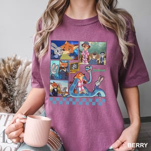 以下が含まれることがあります： アニメ映画「ズートピア」のキャラクターが描かれたコミックストリップデザインのベリーカラーTシャツ。キツネとウサギの画像が含まれており、緑色で「Zootopia」の文字が描かれています。