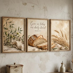 Könnte beinhalten: Set aus drei gerahmten Kunstdrucken mit rustikalem Thema. Ein Druck zeigt Olivenzweige, ein anderer ein Brotlaib mit dem Text "Give us today our daily bread" und der dritte Weizen. Die Rahmen sind aus Holz.