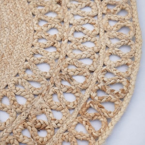 May include: A close-up of a natural fibre rug with a woven design. The rug is made of jute and has a natural beige colour.