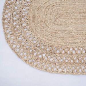 May include: An oval rug made from natural fibres with a woven design. The rug is light brown in colour and has a delicate lace trim.
