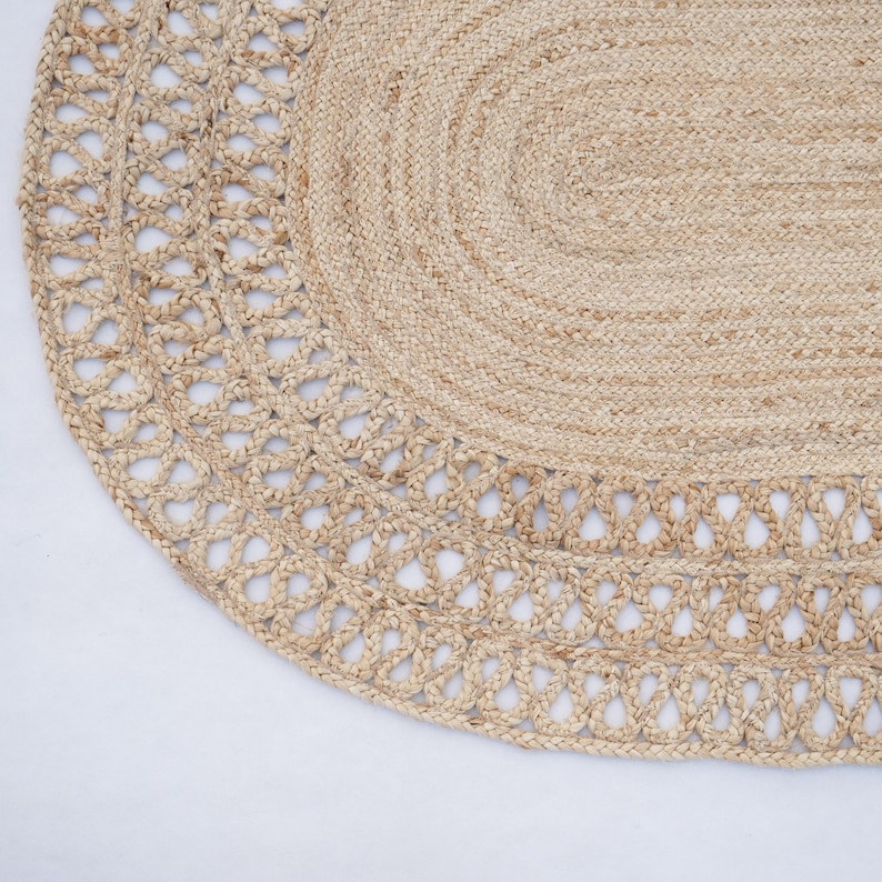 May include: An oval rug made from natural fibres with a woven design. The rug is light brown in colour and has a delicate lace trim.
