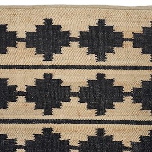 May include: A natural fiber rug with a geometric pattern in black and beige. The rug has a woven texture and a simple design.