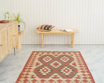 May include: A rectangular area rug featuring a geometric pattern in shades of terracotta, cream, and dark grey. The rug has a repeating diamond motif across the centre and a fringed edge, laid flat on a light-coloured marble floor.