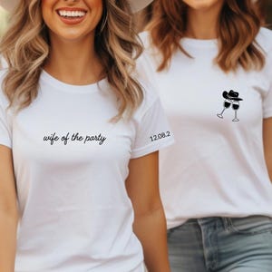 Op de afbeelding: Drie vrouwen dragen witte t-shirts, blauwe jeans en witte hoeden. Eén shirt zegt "wife of the party", en andere hebben een afbeelding van een cowboyhoed en wijnglazen. De datum "12.08.2" staat op de mouw.