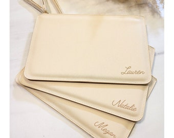 May include: Three beige zippered pouches with the names "Lauren", "Natalie", and "Megan" embroidered in gold on the front.