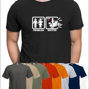 Peut inclure: Un t-shirt noir avec un graphique blanc représentant un couple qui se dispute et une moto avec le texte "Problème résolu". Le t-shirt est disponible dans une variété de couleurs, notamment le gris, le beige, le vert, l'orange, le rouge et le bleu.