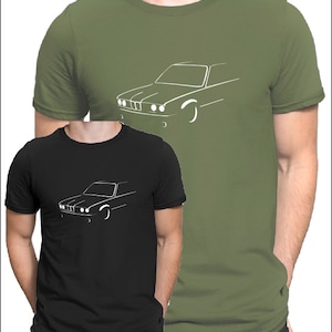 Könnte beinhalten: Zwei T-Shirts mit einer weißen Umrandung eines Autos auf der Vorderseite. Das Shirt links ist schwarz und das Shirt rechts ist grün.