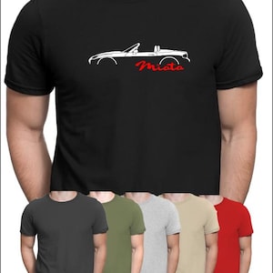 Può includere: Una maglietta nera con una silhouette bianca di un'auto convertibile e la parola "Miata" in rosso.