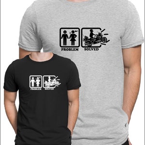 Peut inclure: Deux t-shirts avec un graphique représentant un couple de personnages bâton avec une bulle de dialogue montrant la femme criant sur l'homme. Le deuxième graphique montre un homme conduisant une moto avec les mots "Problème résolu" sous les graphiques.