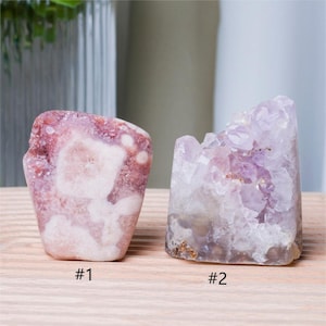 May include: Two amethyst crystal clusters, one with a pink and white color and the other with a purple and white color. The crystals are labeled #1 and #2.