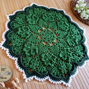 Hand crocheted doily in light emerald green with dark green trim border edged with white little waves. Medium thickness yarn creating creative embossed shamrocks in a circle around the center of the piece.