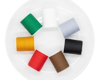May include: A white plate with eight spools of thread in different colors: white, green, yellow, red, brown, black, and two shades of gray.