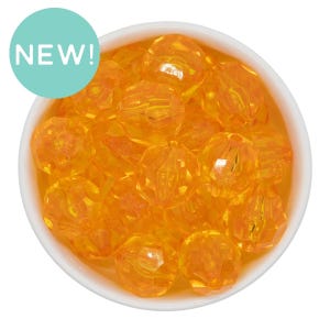 May include: A close-up shot of a white bowl filled with faceted, orange-colored beads. The beads have a crystal-like appearance and are clustered together. A light blue circle with the word "NEW!" in white is in the upper left corner.
