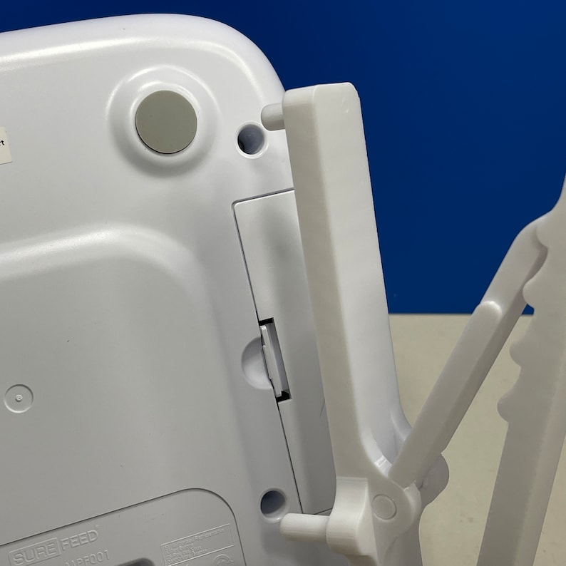 Puede incluir: Una b&aacute;scula de cocina digital blanca con un soporte plegable. La b&aacute;scula tiene una pantalla negra y un bot&oacute;n blanco en la parte delantera. El soporte es de pl&aacute;stico blanco y tiene una bisagra que le permite plegarse.