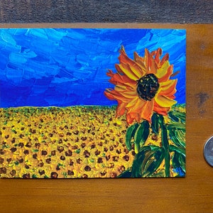 May include: A painting of a field of sunflowers with a single sunflower in the foreground. The sunflower is orange and yellow with a dark brown centre. The background is a blue sky with white clouds.