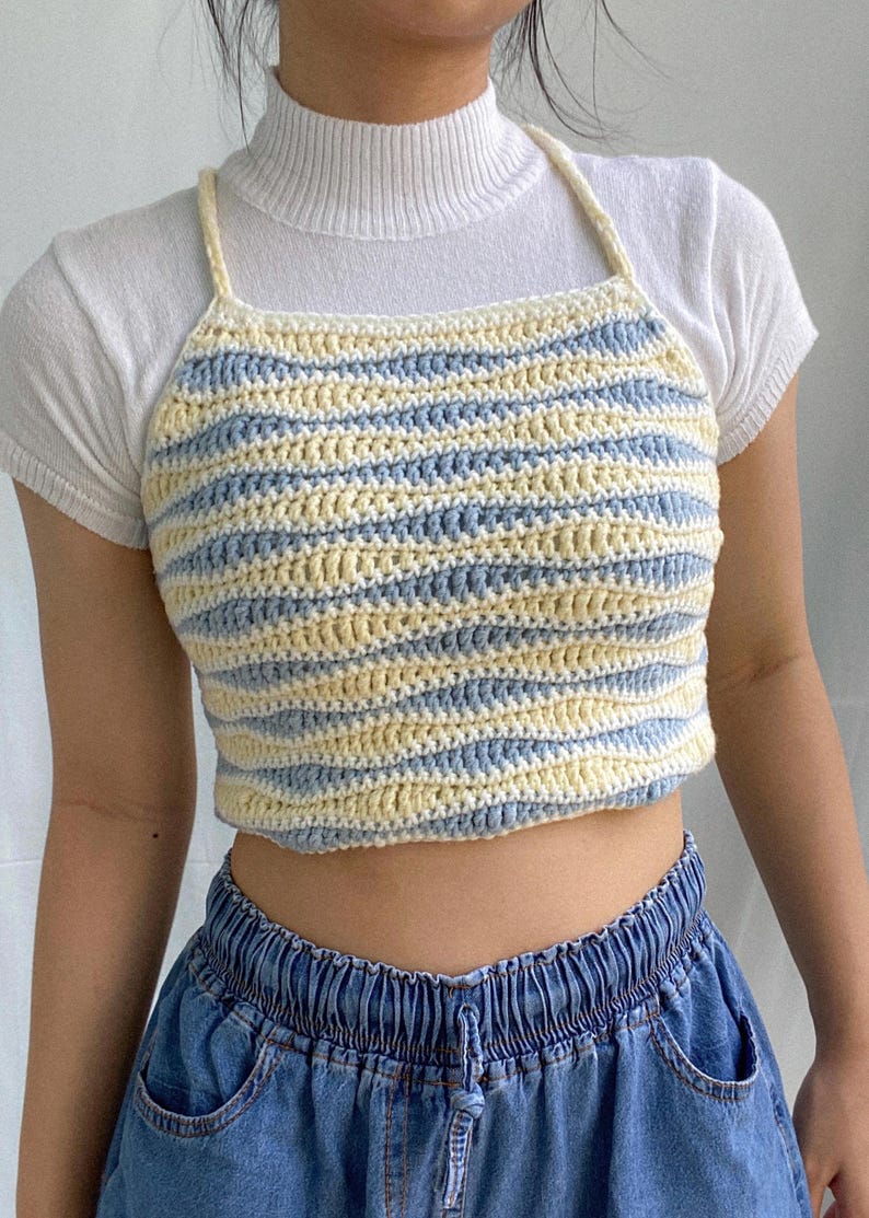 May include: A blue and cream striped crochet crop top with thin straps.