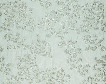 May include: A light blue fabric with a silver embroidered floral pattern. The fabric has a subtle texture and a delicate, feminine feel.