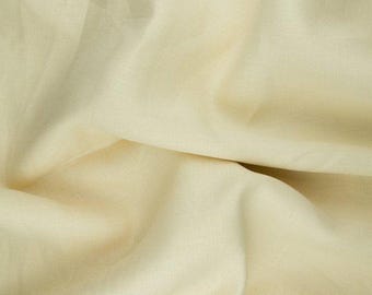 May include: A close-up of a smooth, off-white fabric with a subtle texture. The fabric is folded and draped, creating soft folds and curves.